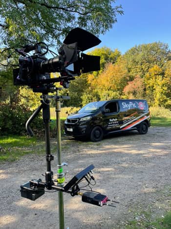 Un appareil photo sur un trépied avec une camionnette en arrière-plan.