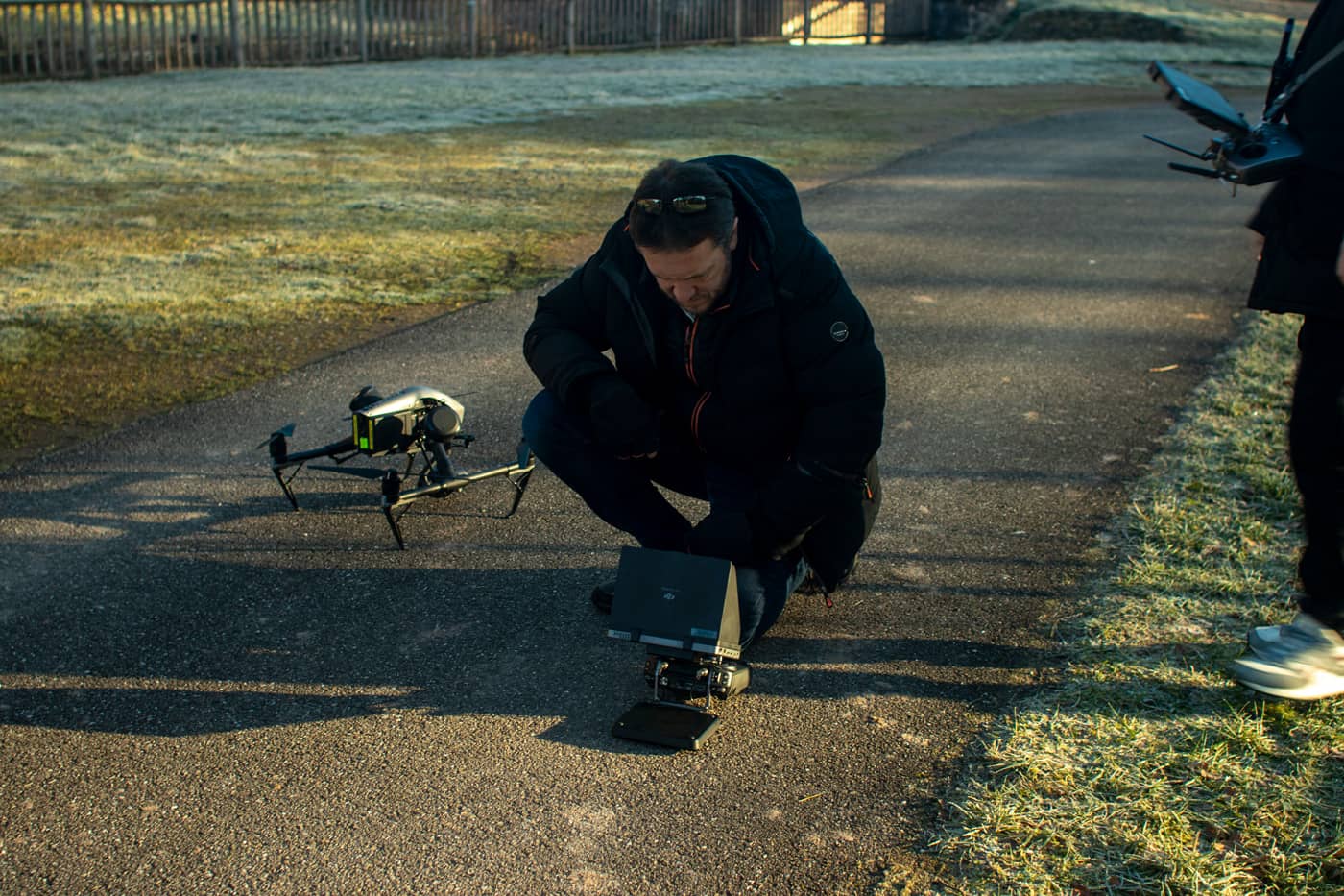 Un homme agenouillé au sol avec un drone devant lui.