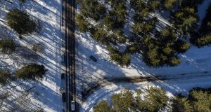 Une vue aérienne par drone d'une route enneigée et d'arbres.