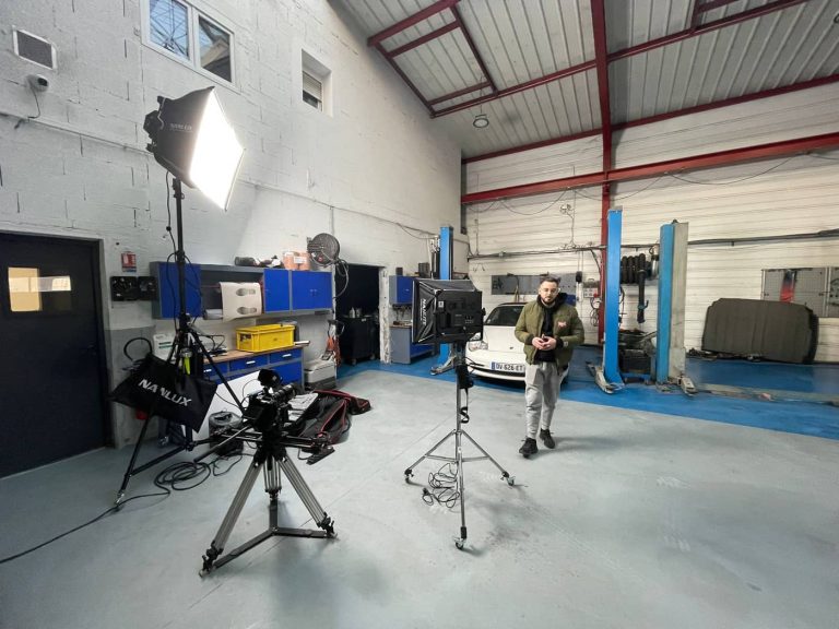 Un homme debout devant une caméra dans un garage.